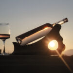 Une bouteille et un verre de vin rosé posés sur un support e