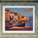 Photographie d'une œuvre d'art d'exception exposée chez Mas Ermitage - Antiques & Design à Saint-Tropez. Ce tableau à l'huile encadré dépeint une scène de marine traditionnelle avec des pointus amarrés devant les façades colorées du vieux Saint-Tropez. Cliché artistique réalisé pour l'édition de Juin 2026 de THE Magazine.