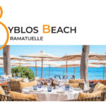 Reportage exclusif réalisé pour l'édition de Juin 2026 de THE Magazine au restaurant de plage Byblos Beach à Ramatuelle. Vue d'une élégante table ronde dressée face à la mer Méditerranée, sous les parasols emblématiques de l'établissement. Crédit photo d'origine : Alexandre Chaplier.